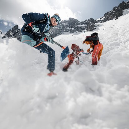 avalanche courses in the snow with three people using shovels and probes